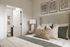 Cozy bedroom with elegant decor, featuring cushioned pillows, soft lighting, and botanical artwork, adjacent to a modern bathroom.