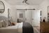 Charming bedroom with a cozy bed, modern sliding barn door, sleek ceiling fan, and elegant wall art, perfect for relaxation.