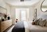 Inviting bedroom with elegant decor featuring a cozy bed, stylish pillows, a wooden dresser with modern lamps, and abundant natural light through large windows.