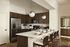 Elegant modern kitchen with sleek stainless steel appliances, dark wood cabinetry, and a stylish breakfast bar with plush seating.