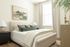 Inviting bedroom with elegant decor, featuring a plush bed, modern artwork, and abundant natural light through large window.