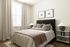 Bright and cozy bedroom featuring a plush bed with elegant pillows, soft lighting, and modern decor for a serene atmosphere.
