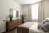 Cozy bedroom with elegant wooden dresser, a stylish mirror, and natural light streaming through large windows.