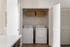 Sleek laundry nook with modern washer and dryer, complemented by elegant wicker storage baskets.