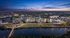 Captivating twilight aerial view of a modern apartment complex, surrounded by lush greenery and reflecting water, offering a perfect blend of urban luxury and serene nature.