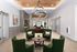 Elegant apartment lounge showcasing a modern chandelier, chic green armchairs, and a stylish circular table, offering a warm and inviting atmosphere.