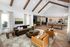 Elegant open-concept living area with vaulted ceiling, featuring modern furnishings, a chic kitchen, and a stylish pool table center stage.