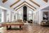 Elegant living room with vaulted ceilings, wooden beams, and a cozy fireplace, featuring a pool table and modern seating.