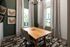 Elegant dining area with a wooden table, stylish chairs, and large windows adorned with patterned curtains for a bright and modern appeal.