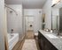 Modern bathroom featuring a sleek granite countertop, stylish tile bath, and spacious walk-in closet.
