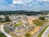 Aerial view of a modern residential community with elegant apartment buildings, spacious green spaces, and inviting pathways, surrounded by lush forested areas.