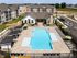 Luxurious apartment complex with a large swimming pool, modern lounge areas, and stylish architecture surrounded by verdant greenery.