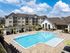 Luxurious apartment complex featuring a sparkling outdoor pool, stylish loungers, and modern architecture under a bright blue sky.