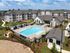 Luxury apartment complex featuring a sparkling swimming pool, surrounded by modern buildings and lush landscaping, perfect for sophisticated living.