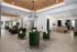 Elegant apartment lounge area featuring modern lighting, green armchairs, and a spacious open floor plan with natural wood accents.