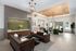 Elegant living area with modern chandeliers, plush seating, and a stylish feature wall, leading to a scenic outdoor view.
