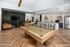 Luxurious apartment interior featuring a stylish billiard table, cozy living area with modern seating, and a contemporary kitchen with barstools.