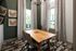 Chic dining area with a modern wooden table, elegant chairs, patterned drapes, and stylish wall art, offering a bright and inviting atmosphere.