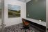 Modern home office featuring a stylish brown chair, sleek gray desk, and vibrant landscape artwork, ideal for productivity.