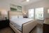 Bright and inviting bedroom with a plush bed, stylish decor, and large windows for natural light.