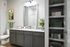 Elegant bathroom with a sleek granite countertop, modern gray cabinetry, art piece, and plush green towels, offering stylish comfort and ample storage.