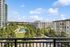 Scenic apartment view with lush greenery and modern architecture under a bright blue sky.