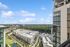 Breathtaking high-rise view overlooking modern urban apartments and lush green landscapes under a vibrant blue sky.