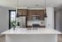 Modern kitchen with sleek white countertops, stainless steel appliances, and stylish wood cabinets, enhanced by elegant pendant lighting.