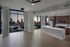 Modern open-plan apartment with stylish kitchen, floor-to-ceiling windows, and breathtaking cityscape views at sunset.