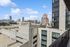 Stunning cityscape view from a modern high-rise apartment balcony, showcasing a vibrant urban skyline under a clear blue sky.