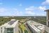 Breathtaking aerial view of a modern cityscape featuring lush greenery, contemporary buildings, and a serene rooftop garden under a clear blue sky.