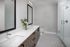 Modern bathroom with elegant double vanity, stylish mirrors, and a glass-enclosed shower with sleek white tiles.
