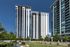 Modern high-rise apartment complex with sleek glass facades, surrounded by lush green landscaping, offering luxurious urban living.