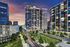 Modern cityscape at dusk featuring stylish high-rise apartment buildings with illuminated windows and vibrant street lights.