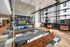 Modern living area with cozy wooden seating, decorative pillows, a wall-mounted TV, and ambient lighting; large windows and chic swings create a stylish, inviting space.