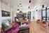 Modern living room with chic gray seating, vibrant pink rug, and stylish hanging chairs by large windows offering an impressive city view.