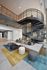 Modern living area with a striking spiral staircase, vibrant rugs, cozy seating, and contemporary design elements.