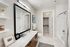 Elegant bathroom with modern vanity, large mirror, and stylish open shelving, leading to a spacious walk-in closet.