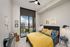 Bright, modern bedroom with stylish decor, featuring a plush bed with colorful linens, elegant wall art, and a private balcony with a beautiful urban view.