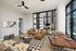 Modern apartment living room with chic decor, featuring a stylish leather sofa, large windows offering a stunning city view, and a wooden dining table set for four.