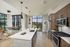 Modern open-concept kitchen with elegant wooden cabinetry, island counter, and stainless steel appliances, overlooking a scenic city view through expansive windows.
