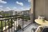 Charming balcony view overlooking modern apartment complex with lush greenery and a cozy seating area.