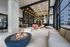 Modern communal lounge featuring a cozy fire pit, chic seating arrangements, and stunning floor-to-ceiling windows with ambient lighting.