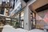 Elegant entrance of a modern city apartment complex with expansive glass windows, contemporary lighting, and vibrant geometric wall art.