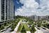 Luxurious urban living with modern high-rise apartments, lush landscaped gardens, and serene pathways under a bright blue sky.