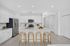 Bright, modern kitchen featuring sleek white cabinetry, stainless steel appliances, and a stylish island with wooden bar stools.