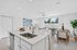 Modern open-concept living space with sleek kitchen island, cozy living room, and elegant dining area overlooking a fenced backyard.