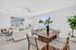 Bright, modern living and dining area with sleek furniture, lush greenery, and a large window view of the garden.