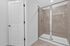 Elegant bathroom featuring a sleek glass-enclosed shower with modern tiles and a pristine white door.