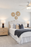 Elegant bedroom featuring a plush bed with textured cushions, tasteful wall decor, and ambient lighting on wooden nightstands.